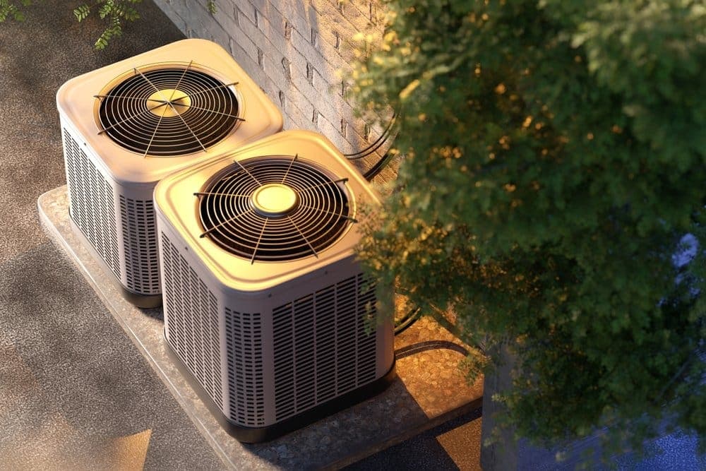 Two newly installed air conditioning condensers on a concrete pad