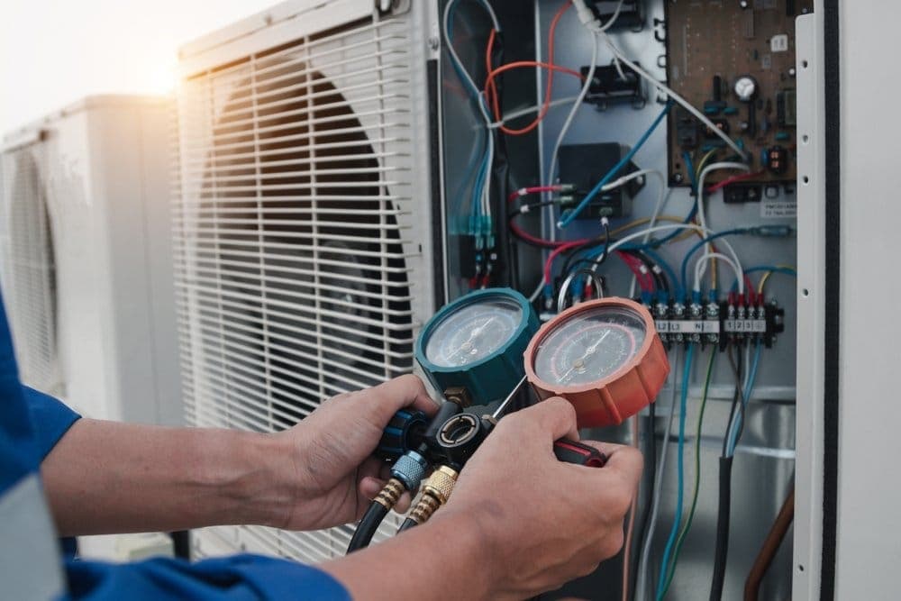 Technician reading refrigerant pressure gauges on an air conditioner