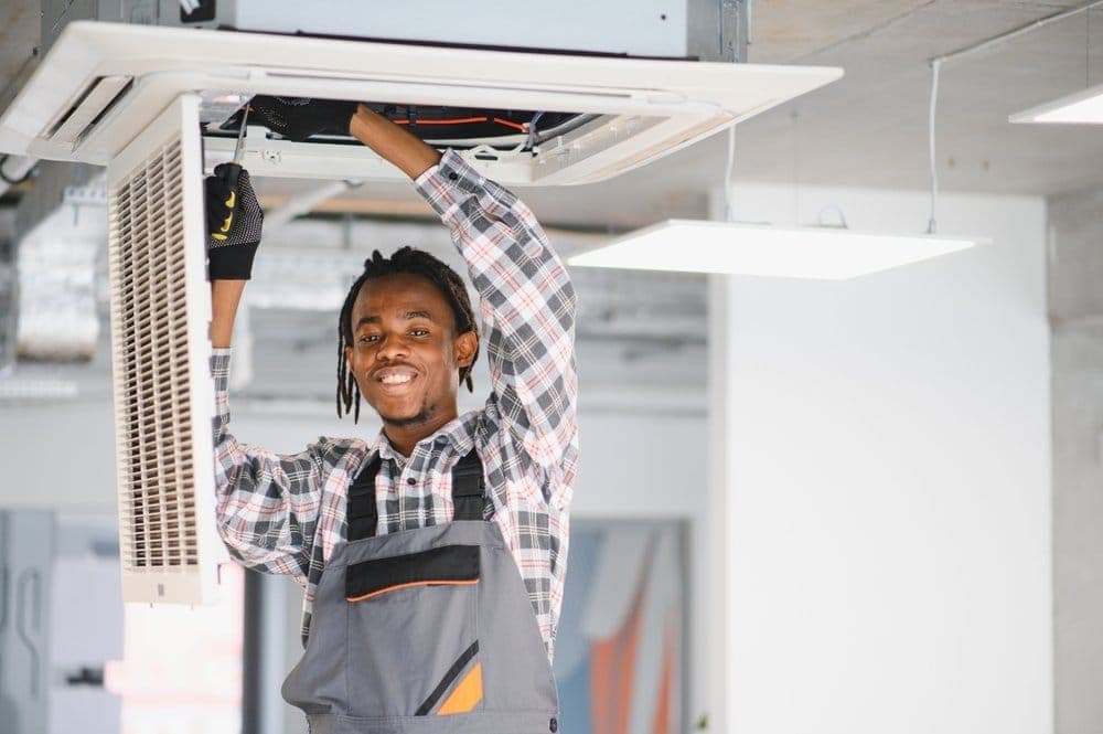 Technician servicing an indoor air conditioning unit